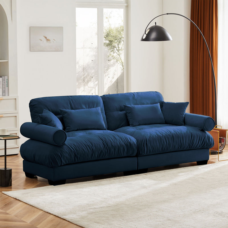 Blue oversized sofa with tufted back cushions, rounded arm bolsters, and throw pillows
