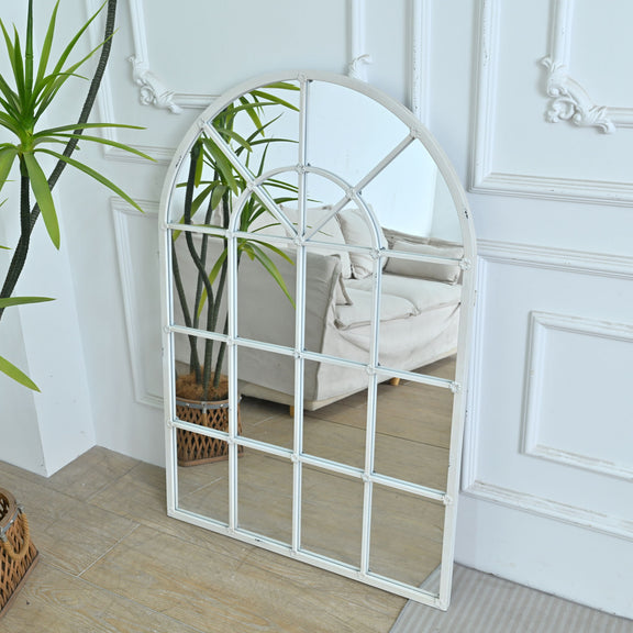 White arched mirror with decorative window grid pattern and reflective surface
