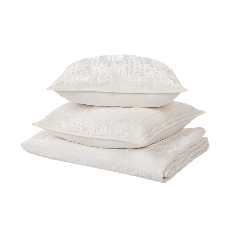 Stacked ivory quilt set pieces with textured quilting and decorative piped edges