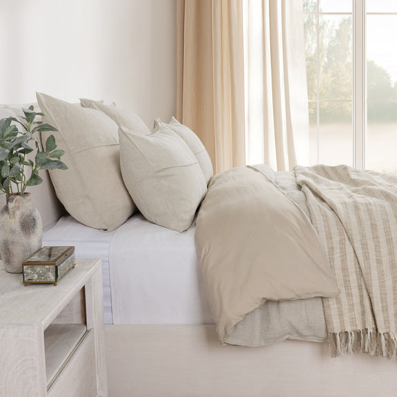 Beige linen sham pillows on a sofa bed with matching throw and blanket