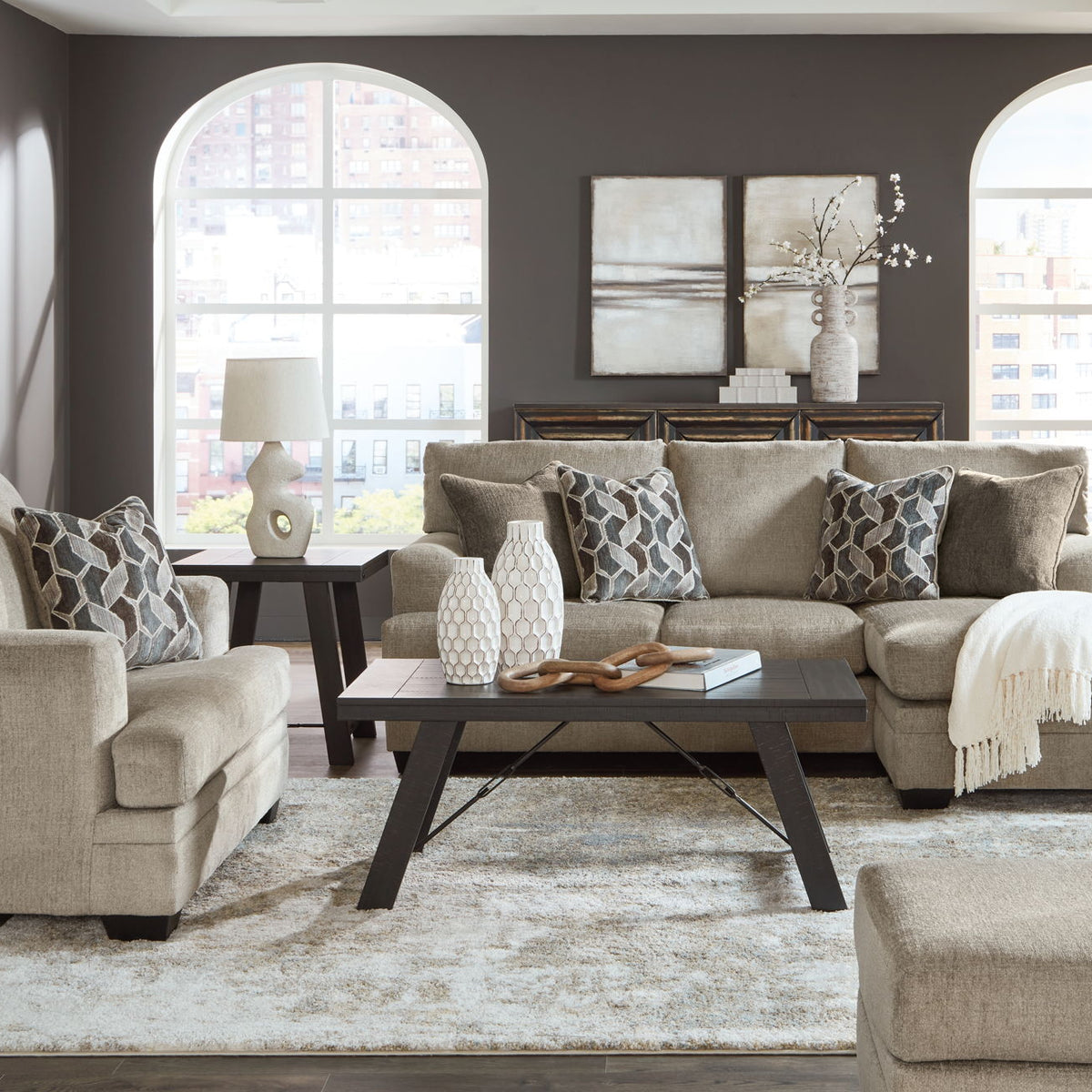 Taupe fabric sofa set with matching chaise chair and tufted accent ottoman in living room.