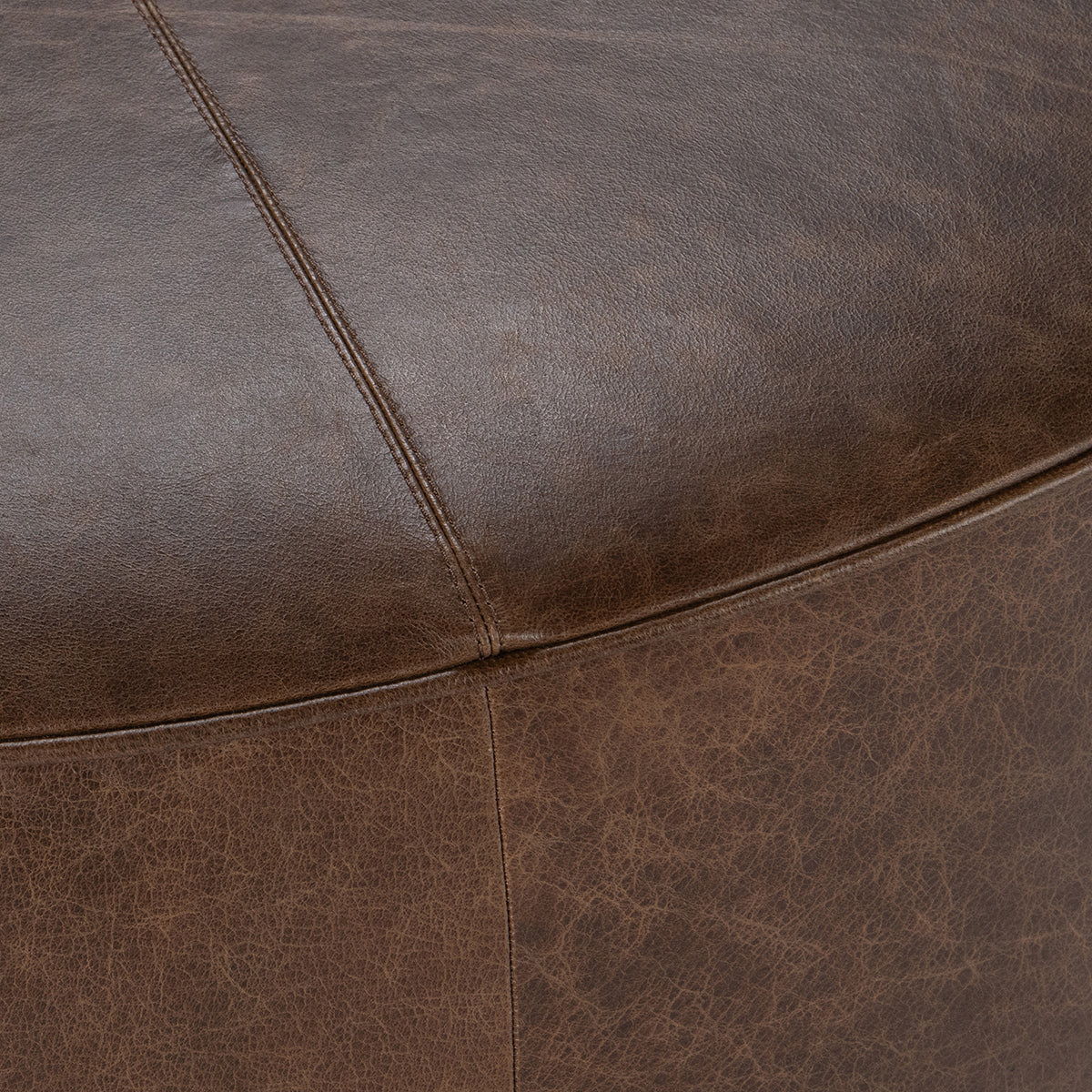 Close-up of brown leather upholstery seams and stitched panel line