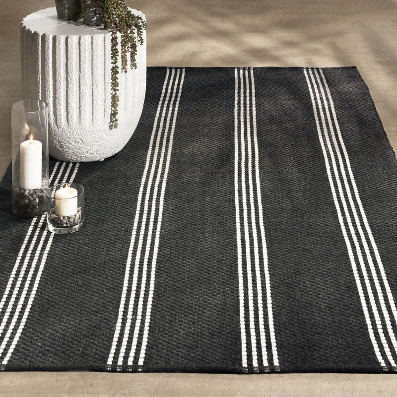 Charcoal rug with wide vertical ivory stripes and textured flat weave