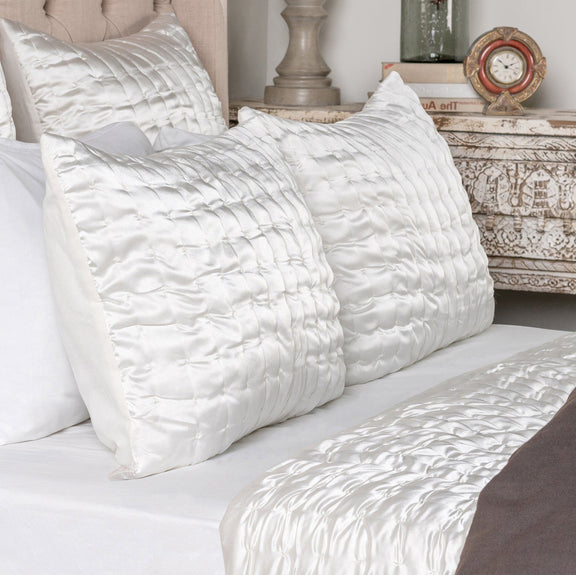 Ivory quilt with channel quilting beside quilted pillow shams on a bed