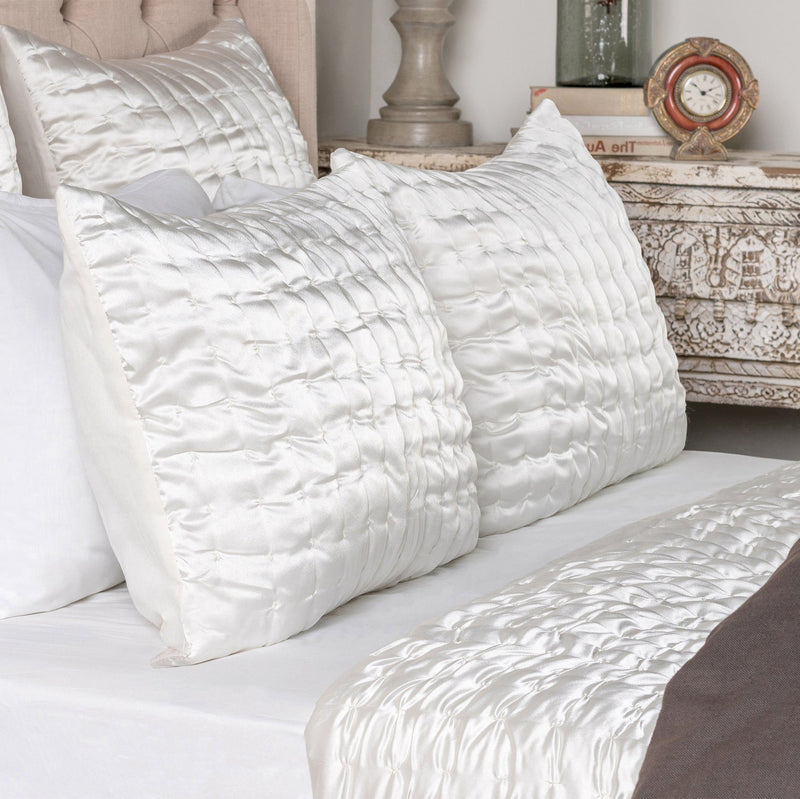 Ivory quilt with channel quilting beside quilted pillow shams on a bed