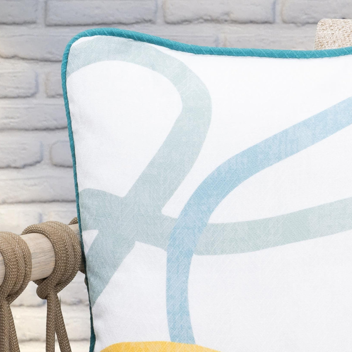 Square cushion close-up with teal-bordered abstract blue and yellow shapes.