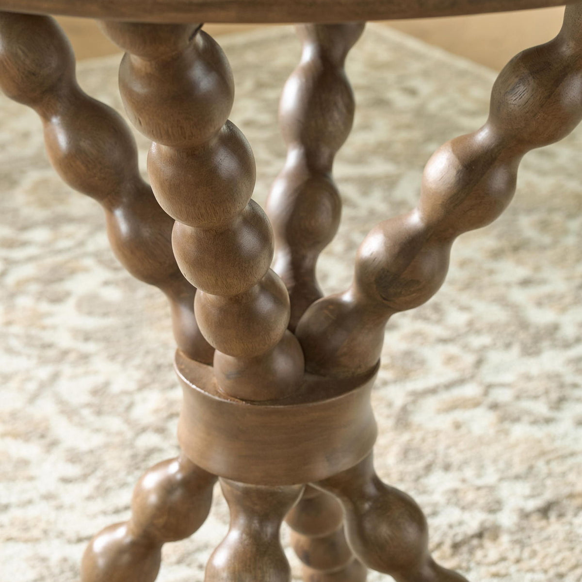 Close-up of light brown accent table turned trestle legs