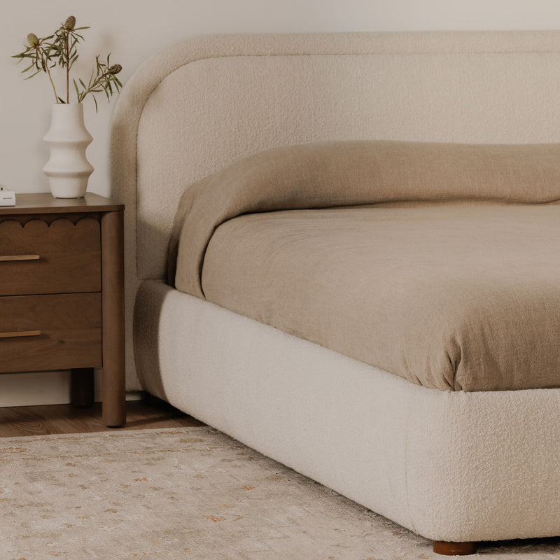 Oatmeal upholstered queen bed side panel with rounded corners and tapered legs