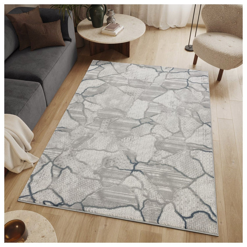 Gray area rug with abstract map-like pattern and blue accents, centered in living room