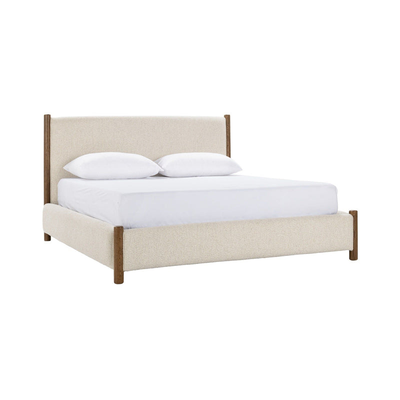 Beige upholstered bed with tall headboard, padded platform base, and wood legs