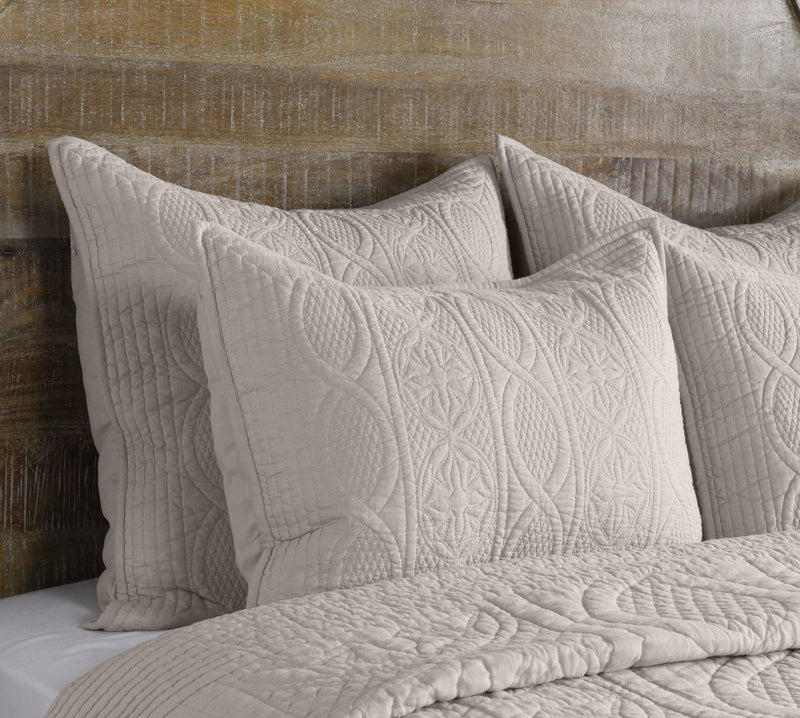 Quilted decorative sham in light taupe with raised oval and floral-style stitching.