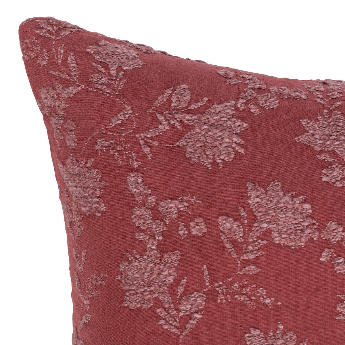 Burgundy red pillow face with light floral vine pattern, close-up texture and stitching.