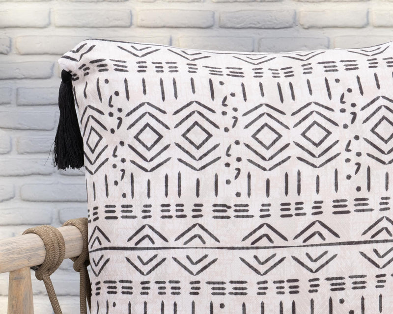 Close-up of natural pillow fabric with black geometric design and tassel fringe.