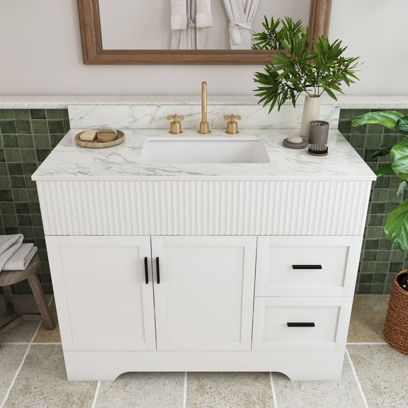 White bathroom vanity with fluted cabinet front, sink basin, and gold faucet set on top