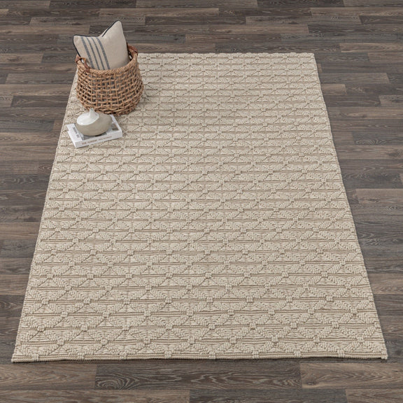 Beige patterned area rug with textured geometric blocks and low, plush pile.