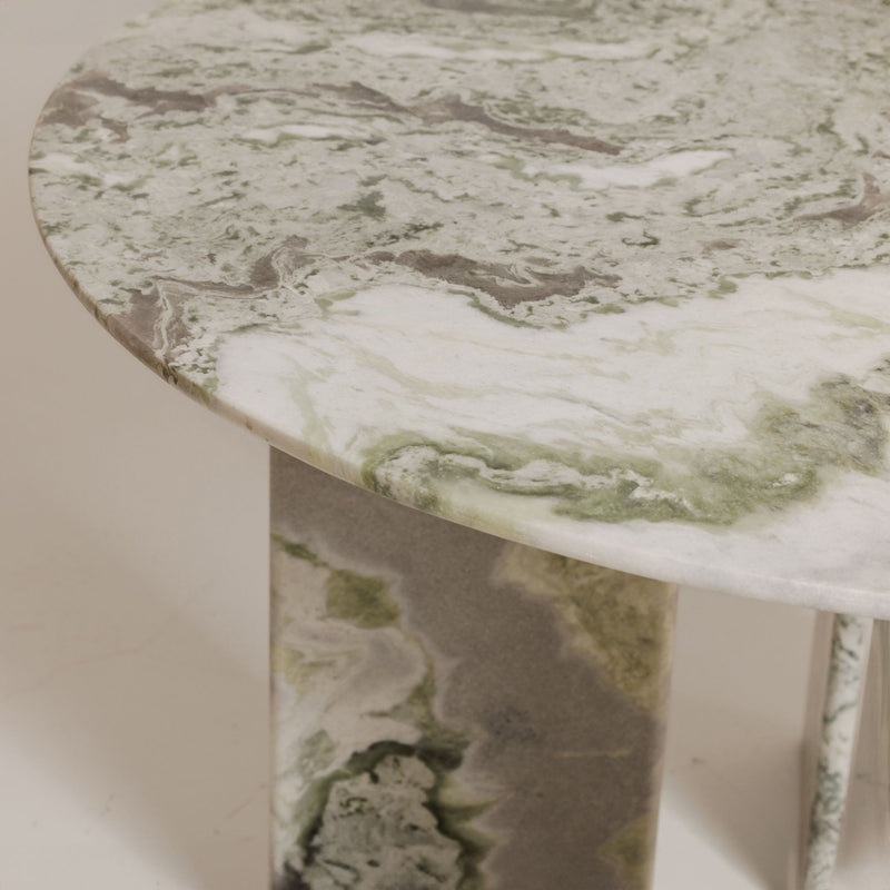Close-up of round dining table top in green veined marble with curved edge
