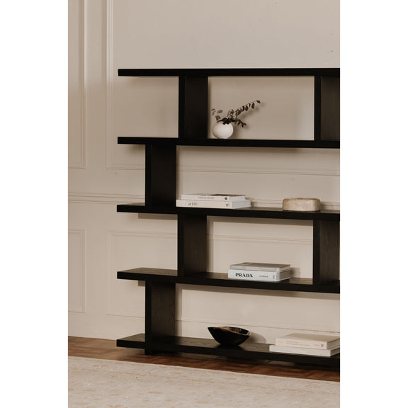 Close view of the black shelf's staggered tiers holding books and decor.