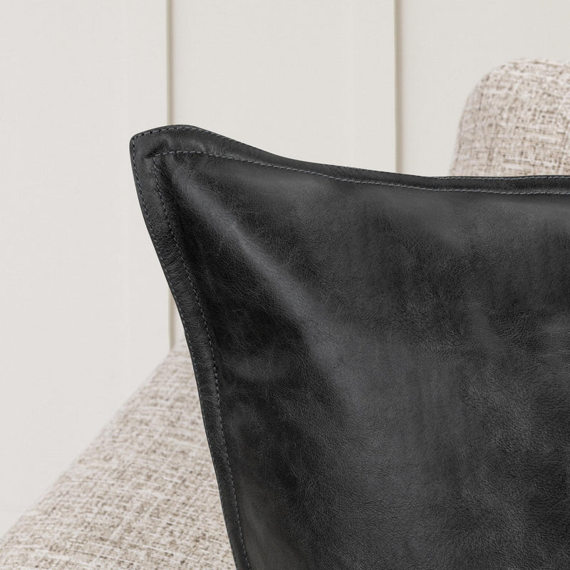 Black leather pillow corner with stitched piping and smooth grain texture