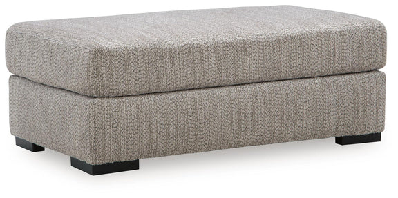 Gray upholstered ottoman with rectangular cushioned top and black feet
