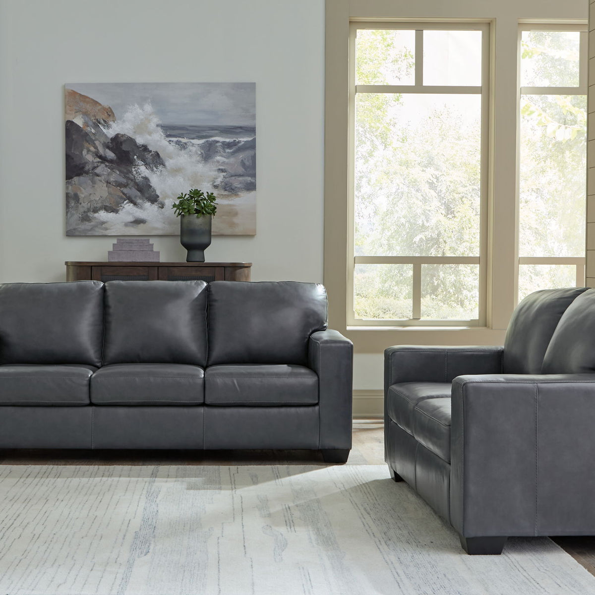 Dark gray upholstered sofa with matching armchair and tufted back cushions
