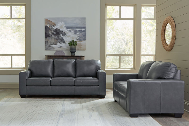 Dark gray upholstered sofa with matching armchair and tufted back cushions