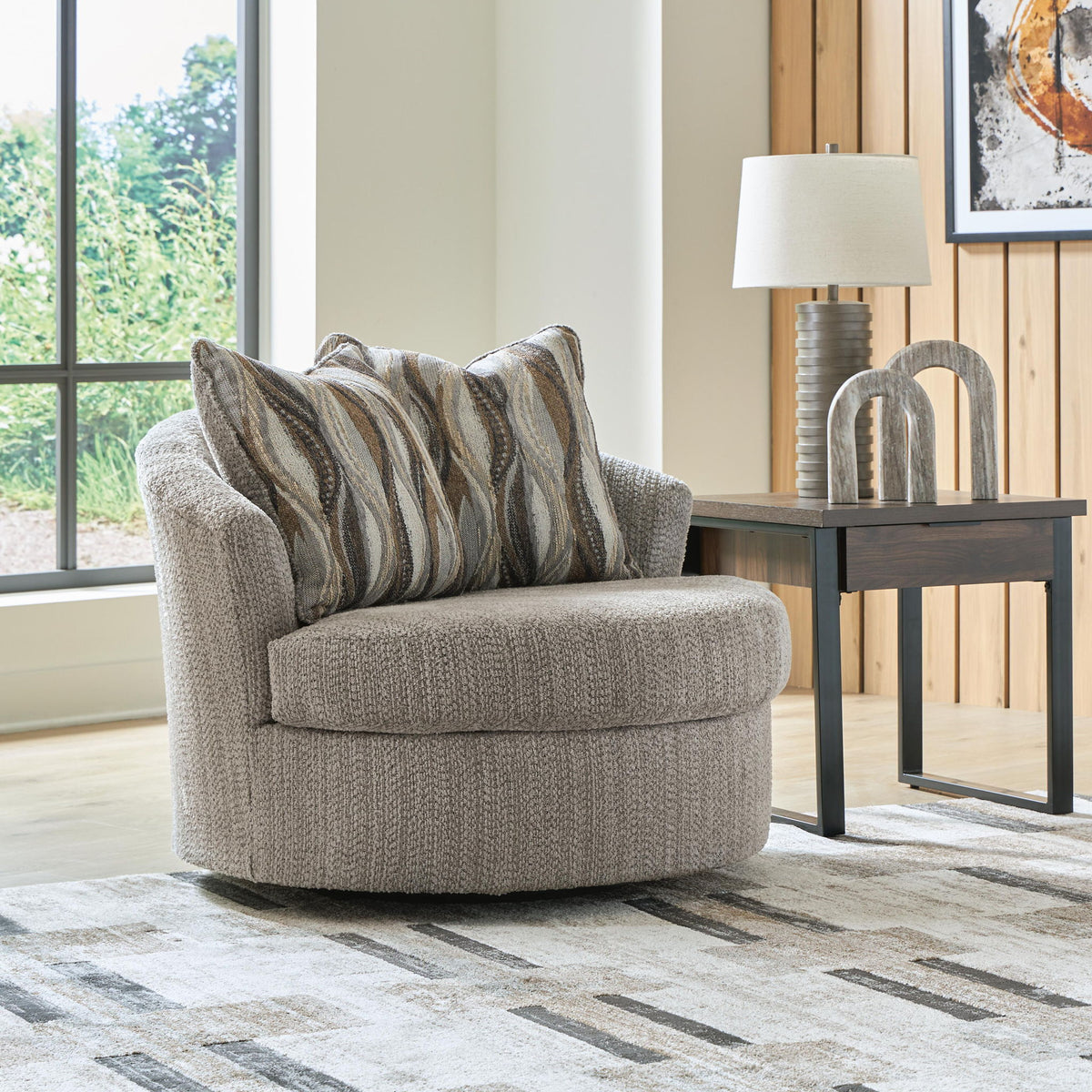 Swivel accent chair with gray textured upholstery and striped lumbar pillows