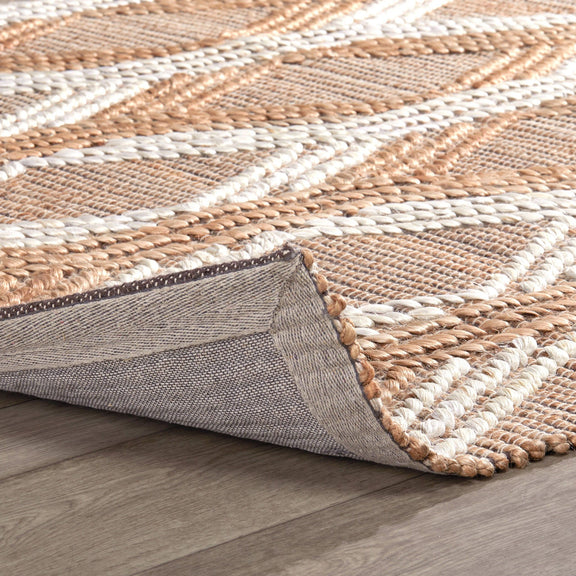 Natural fiber rug edge detail showing woven texture and gray fabric backing.