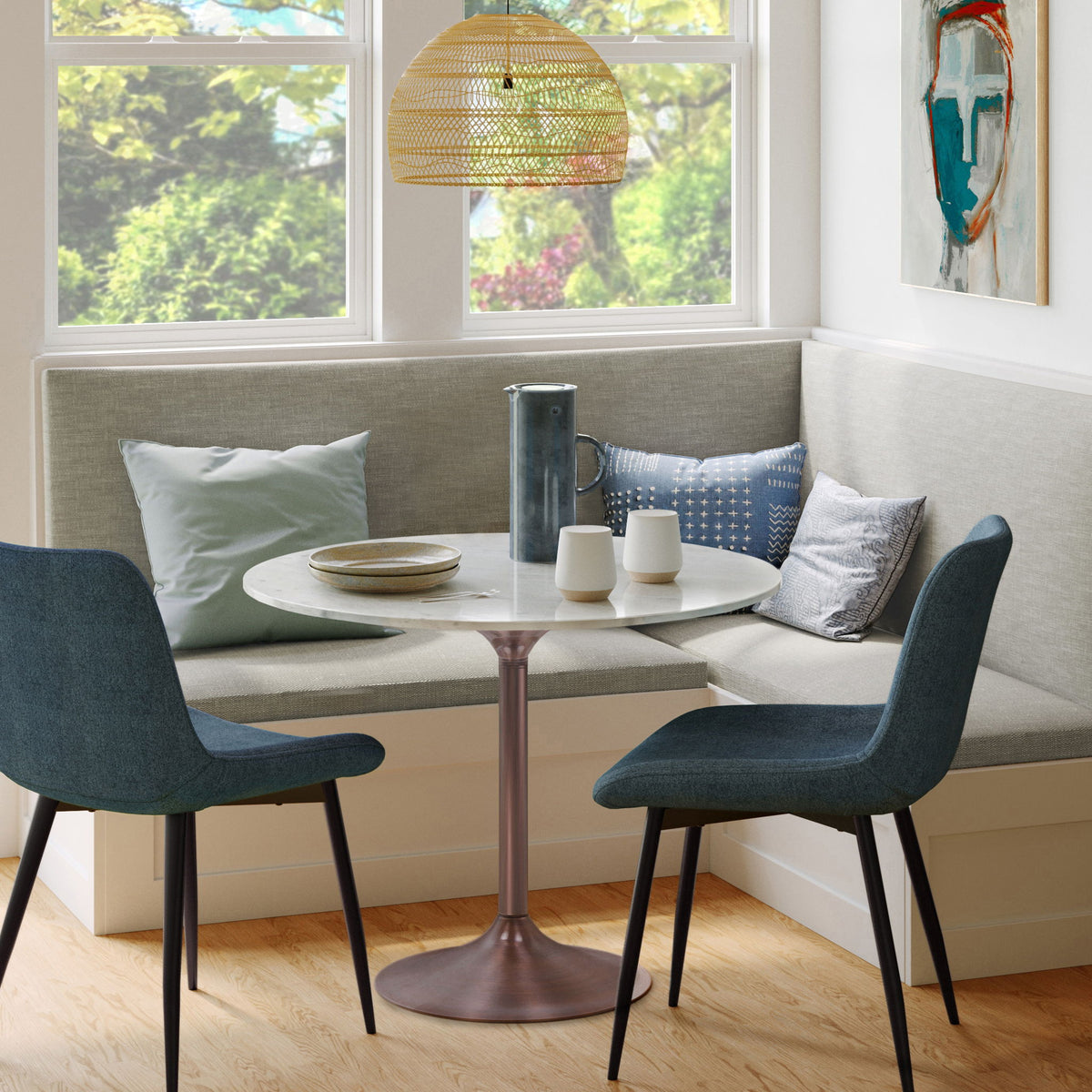 Round dining table with white veined top and copper-tone pedestal base, set for dining