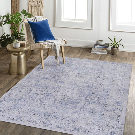 Washable area rug in light blue with abstract distressed pattern and cream accents