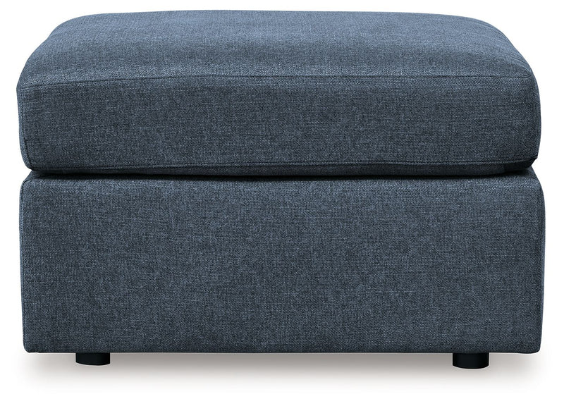 Upholstered ottoman with dark blue fabric, rounded top cushion and low legs