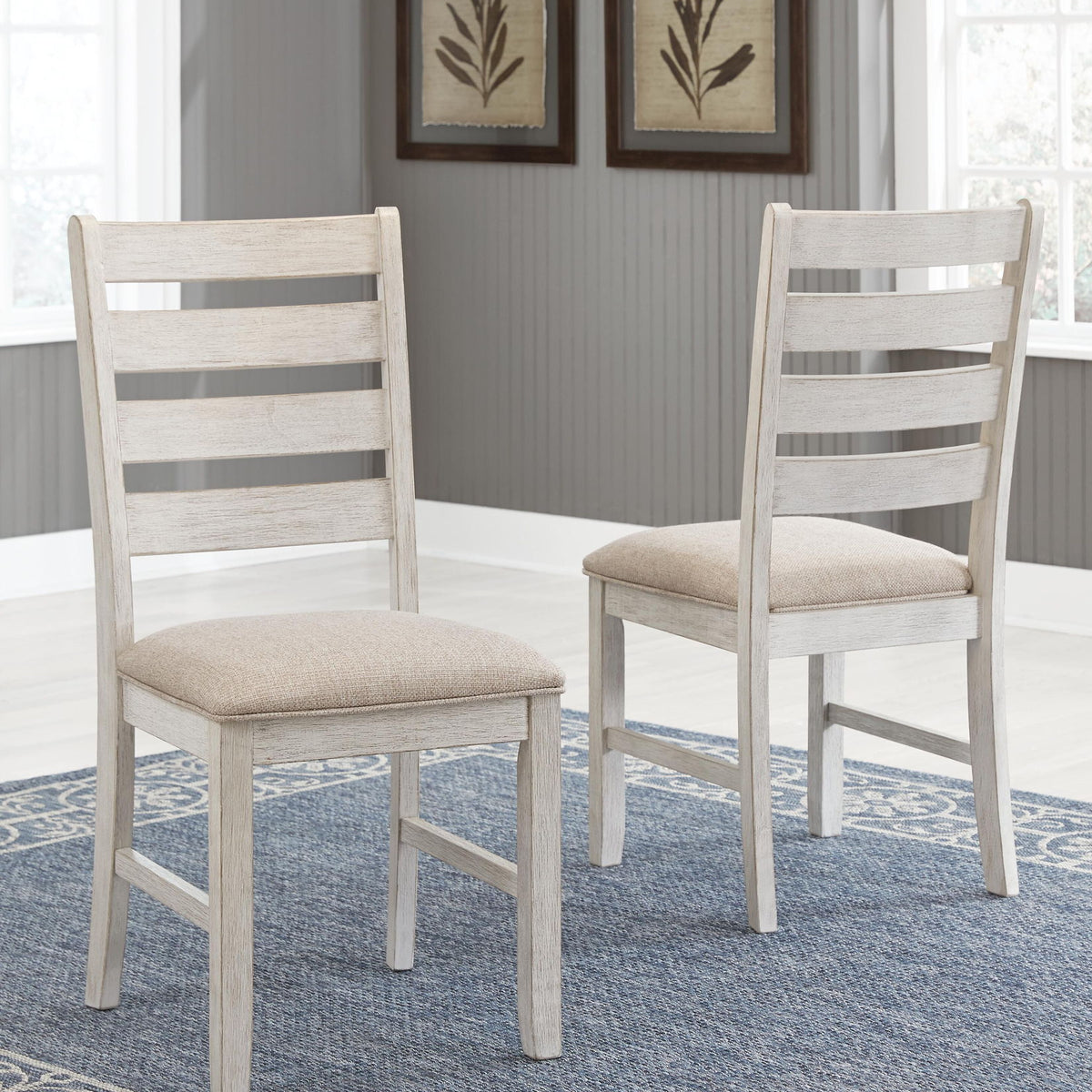 Two white dining side chairs with slatted backs and beige upholstered seats