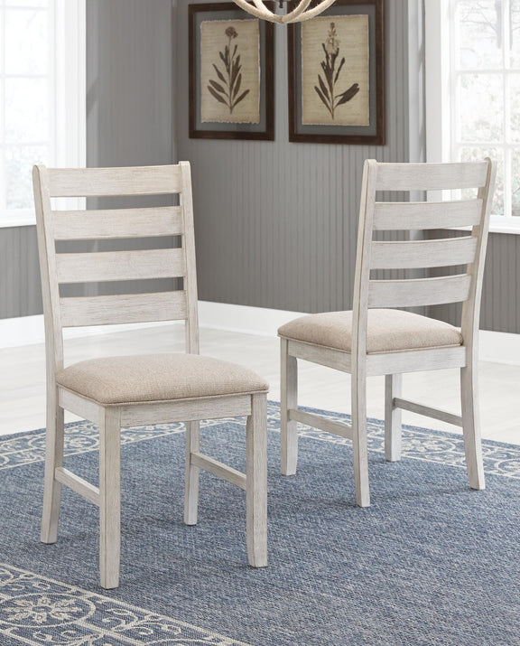 Two white dining side chairs with slatted backs and beige upholstered seats