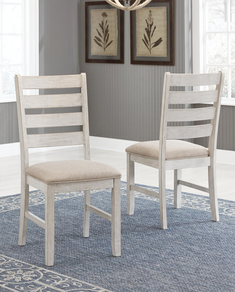 Two white dining side chairs with slatted backs and beige upholstered seats