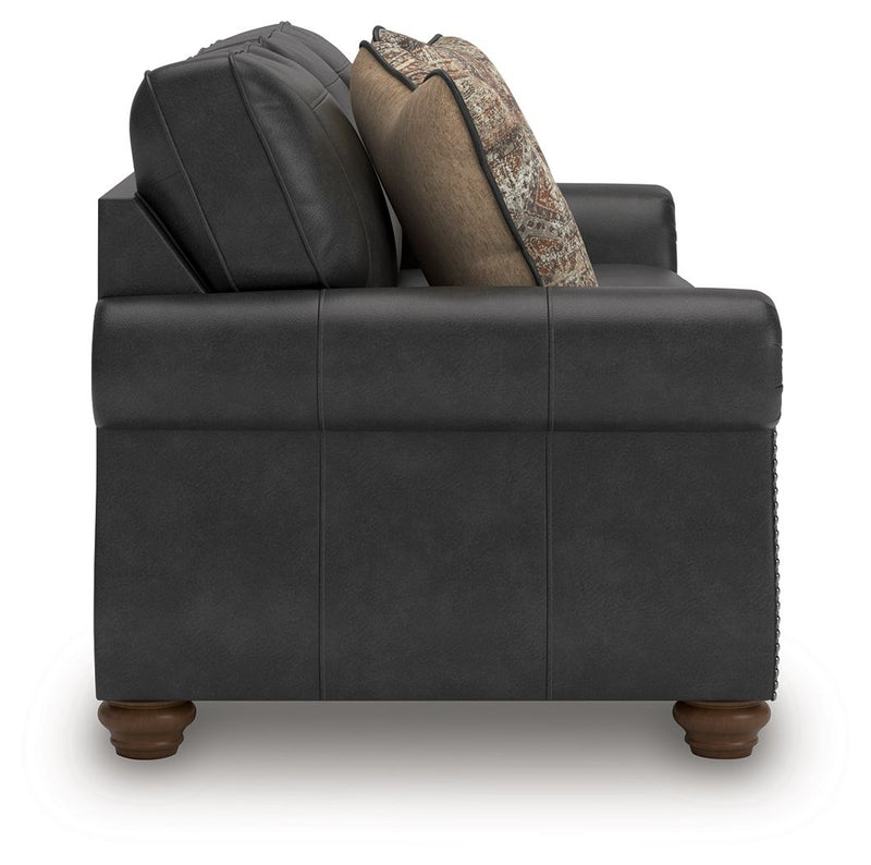 Dark gray sofa viewed from front with three seat cushions and patterned pillows