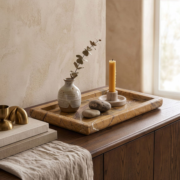 Marble tray with patterned surface holding pillar candle and small decor