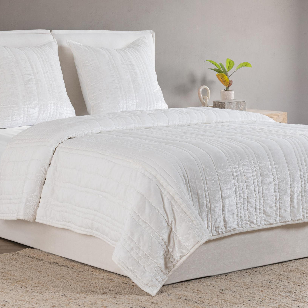 White quilt with quilted stripe pattern and matching pillow shams on bed