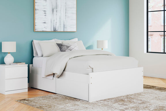 White platform bed with one side storage drawer and layered white bedding