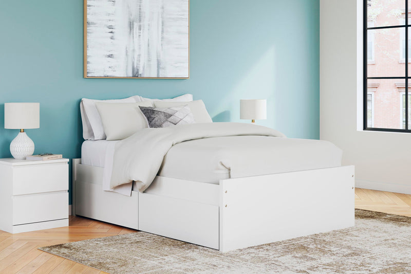 White platform bed with one side storage drawer and layered white bedding