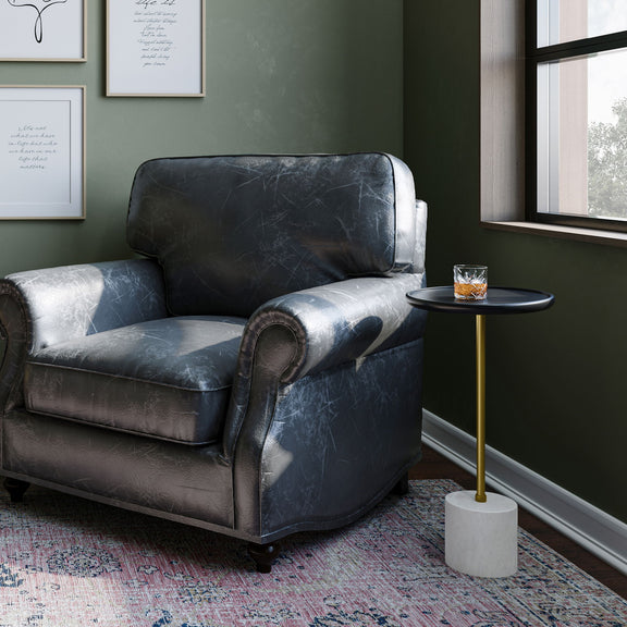 Turner black side table beside an armchair, with a gold stem and white base