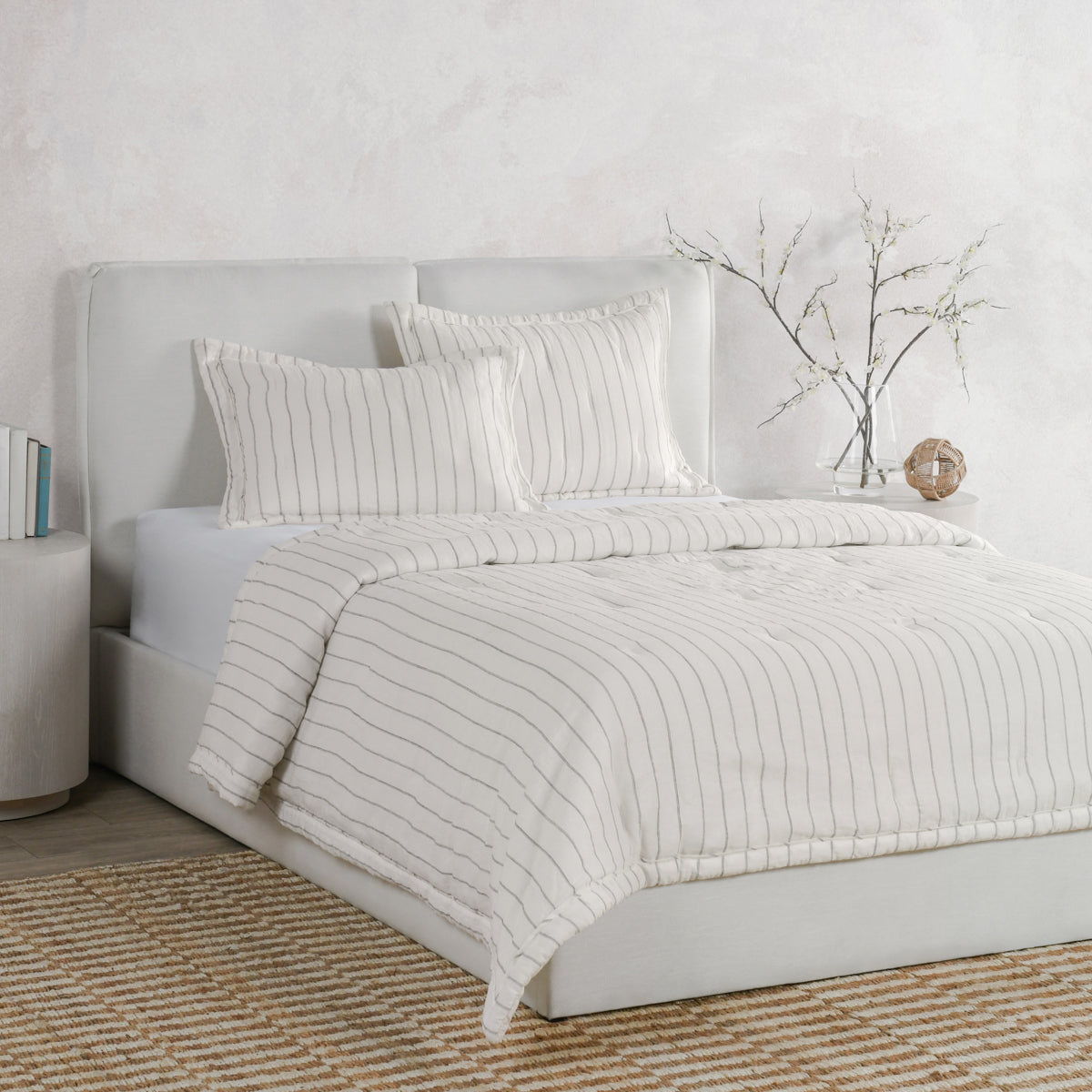 Ivory euro sham with gray wavy stripes on a bed, layered with matching shams