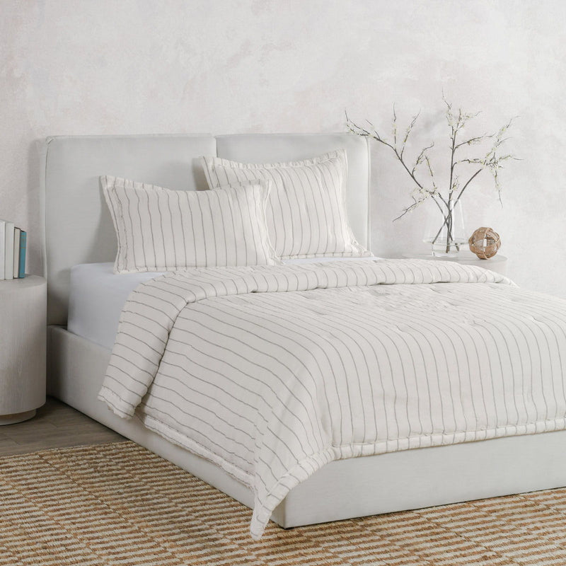 Ivory euro sham with gray wavy stripes on a bed, layered with matching shams