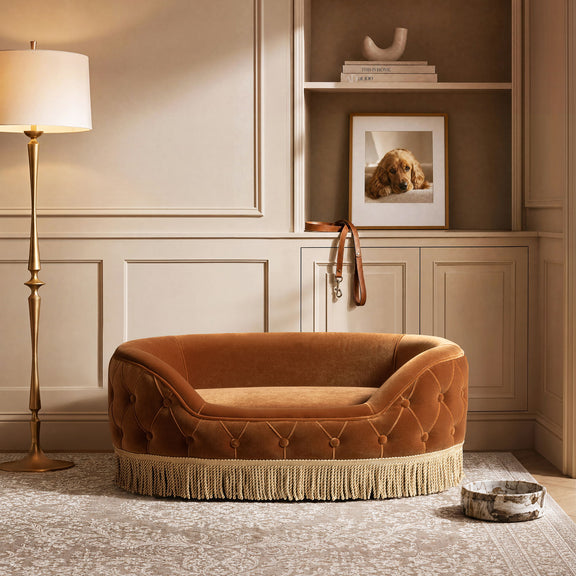 Burnt orange tufted dog sofa bed with open top and fringed skirt