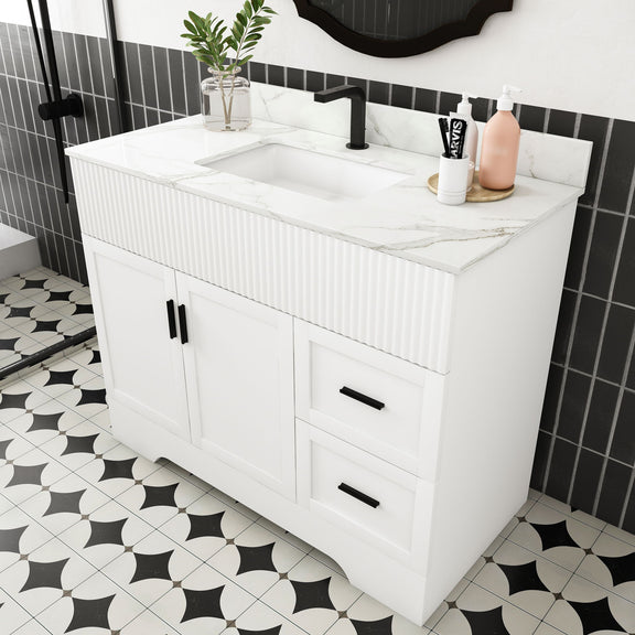 White bathroom vanity with fluted panels, integrated rectangular sink, two doors and two drawers.