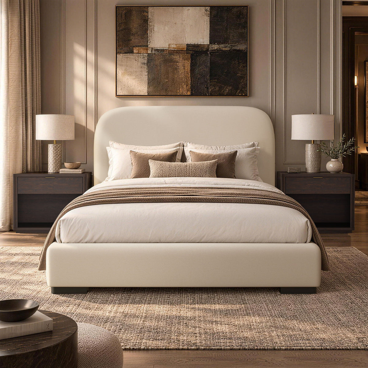 Beige upholstered bed with rounded headboard, layered bedding, and matching upholstered foot