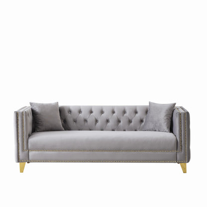 Dark gray sofa with tufted back cushions, square arms, nailhead trim, and gold legs.