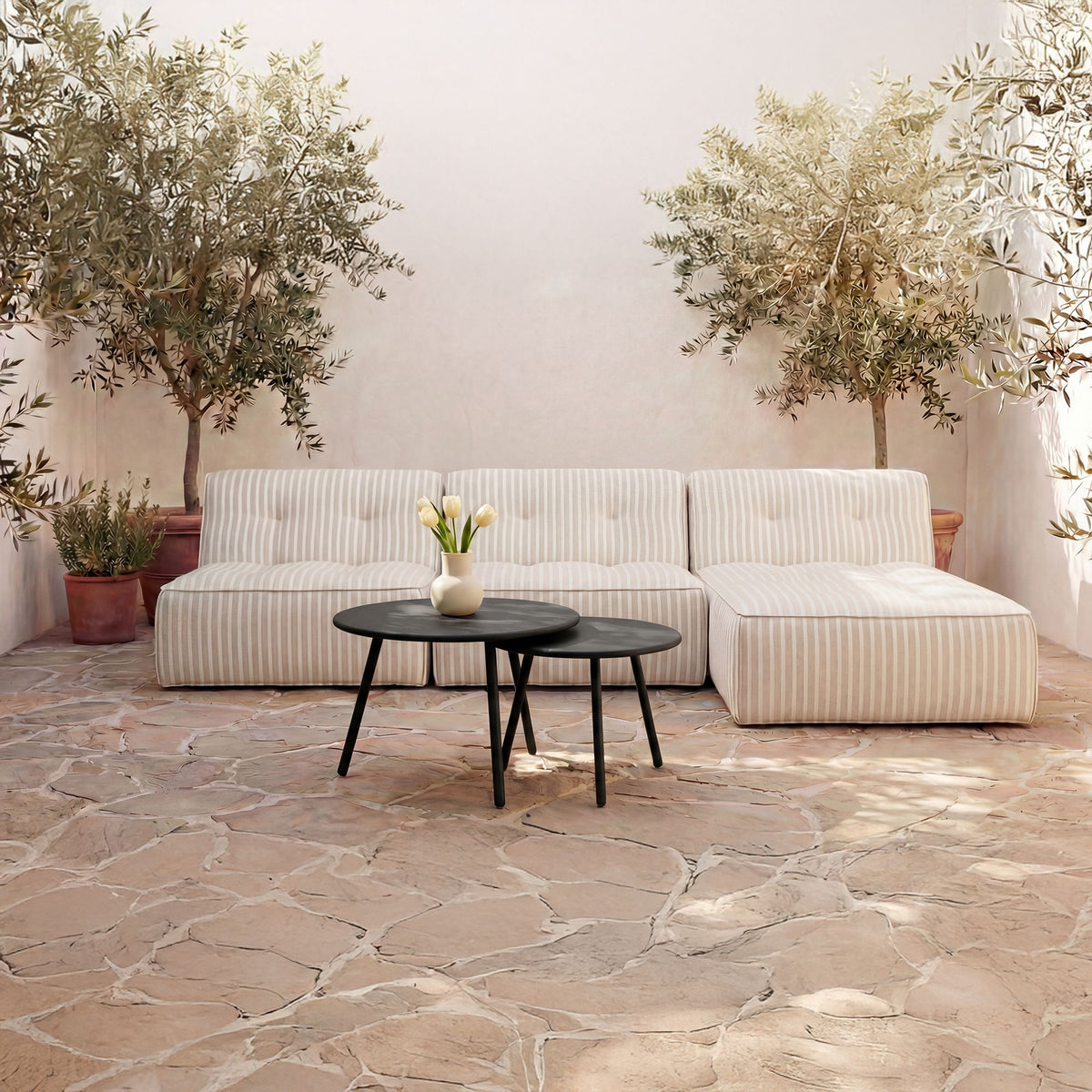 Outdoor patio nesting coffee table set with two black round tables beside striped sofa