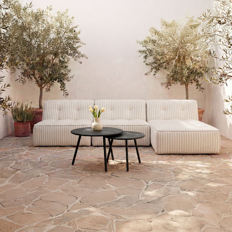 Outdoor patio nesting coffee table set with two black round tables beside striped sofa