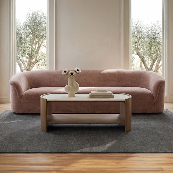 Blush pink sofa with rounded arms and low, cushioned profile seat.