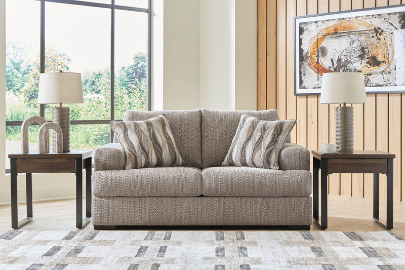 Gray loveseat sofa with striped throw pillows, black legs, and textured upholstery