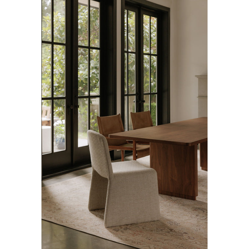 Upholstered beige dining chair with curved backrest and seat, angled view